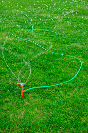 Irrigation System Watering the green grass, blurred waterdrops flying in the air, copyspace on foregroundの写真素材