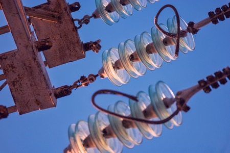Close up of high voltage insulators at power-tower looking upwards from earth