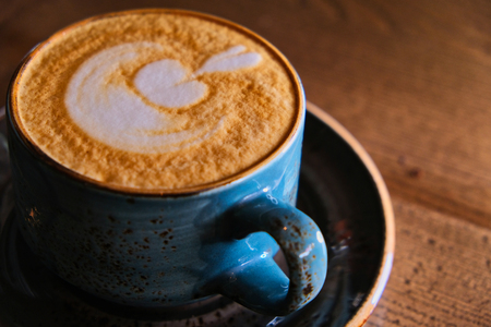 Closeup of blue cappuccino cup on tabletop backlitの写真素材