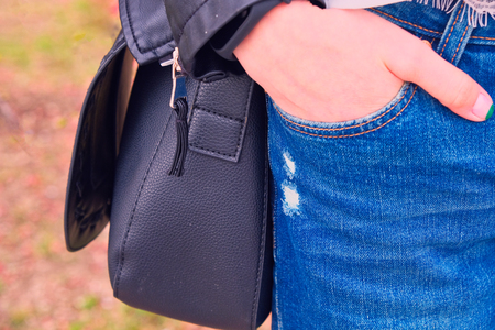 Girl with hand in jeans pocket with black handbag hanging on shouldr closeup toned imageの写真素材