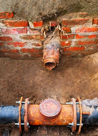 Abandoned destroyed connection of rusty pipes, fragment of the pipe from the red brick wallの写真素材