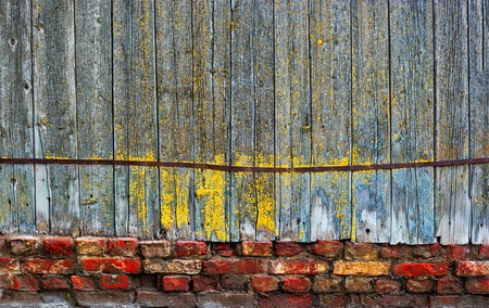 Old wooden fence stands on red brick base and rusty iron ribbon, copy-spaceの写真素材