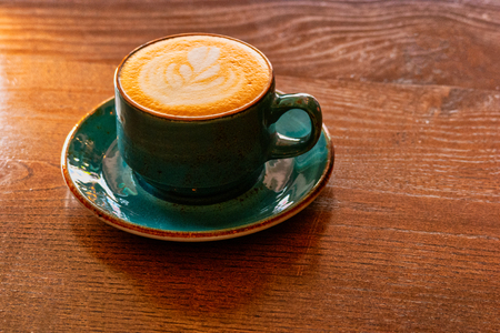 Ceramic Cup Of Green Color Full With Cappuccino On Wooden Table With Copyspaceの写真素材