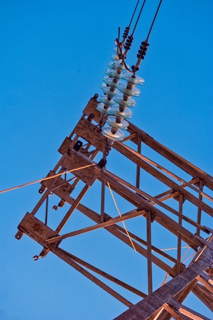 High voltage insulators in row on power tower in front of the skyの写真素材