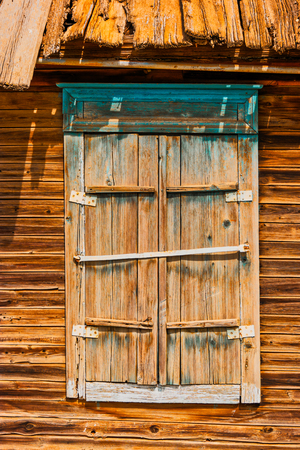 Closed shatters of wooden window made of weathered wood of slum house in Astrakhen Russiaの写真素材