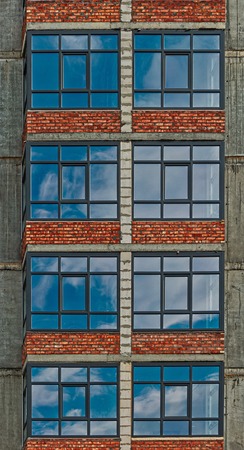 Row of the windowa of apartment building in development state with reflections of blue sky in window glass vertical imageの写真素材
