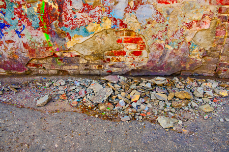 Damaged wall with building garbage beneath on pavement surfaceの写真素材