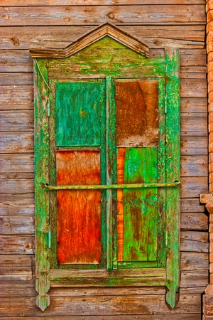 Shabby window of old wooden house painted in green and red color front viewの写真素材