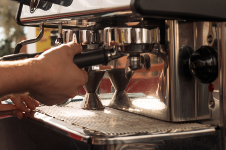 Smallbusines owner preparing espresso using chromed coffee machine side viewの写真素材