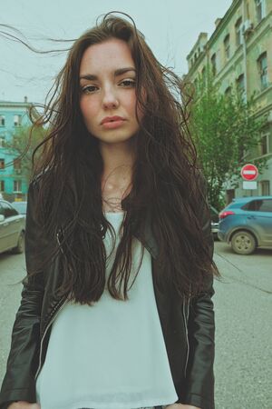 Peaceful looking girl posing with messy windy hair ouside, wide angle smartphone lens imitation vertical imageの写真素材