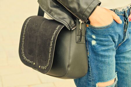 Young woman hold yoyr hand in pocket wih black handbag on her shoulder wearing riped jeansの写真素材