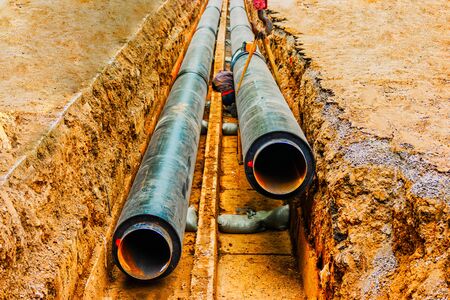 Underground pipe being fixed in trench. Man do a circular welding in trenchの写真素材