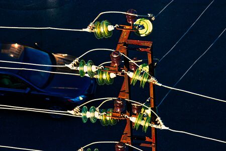 Many sets of glass electric insulators mounted on wires of powertower view from aboveの写真素材
