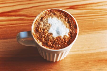 Mug of cappuccino on a wood table In natural light above view.の写真素材