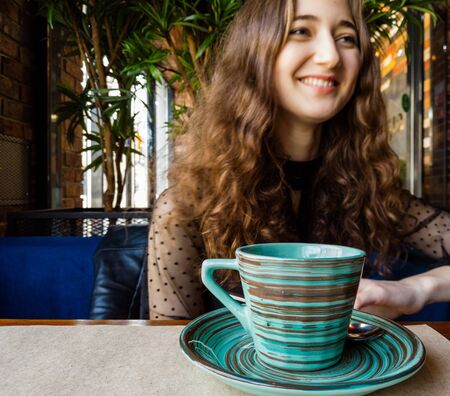 Focus on the cup in the foreground, the laughing girl blurred in the background, copyspaceの写真素材