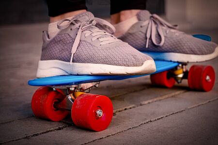 The girl wearied old sneakers is standing on skteboard closeup image