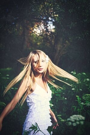 Lady in white dress dancing in the woods with her hair fly in the air, copyspace is over her head. Fairy dance.の写真素材