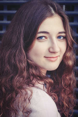 Young lady looking at camera with cute smile. Her long wavy ginger hairs are framing her face. matte vintage look.の写真素材