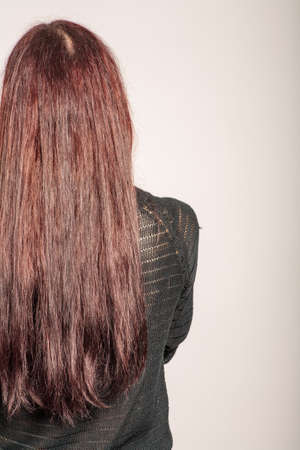 Back view of red haired girl with long straight hair posing on grey background with copyspaceの写真素材