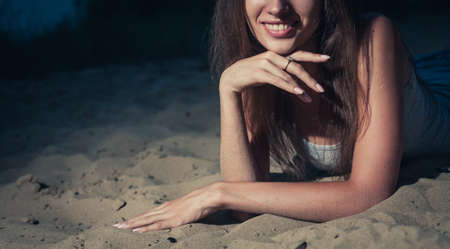 Part of the face of young woman smiling while lying on the sand, shot with copyspace on leftの写真素材