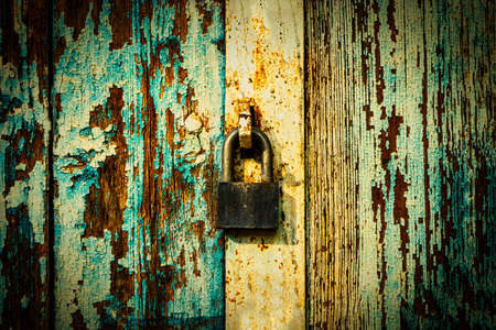 Closed lock on weathered planks of gates painted in blue peeling paintの写真素材