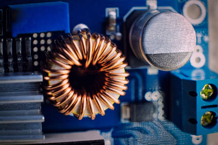 Ferrit inductance coil on electric board wrapped with copper wire along with other components, macro shotの写真素材