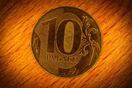 Ten rubles coin with inscription in Russian language - 10 rubles, macro picture on wooden background with vignette. Depicting slang name for ruble - "wooden (currency)".の写真素材