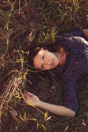 Nice lady dark-haired lying in autumnal grass above view, copyspace.の写真素材