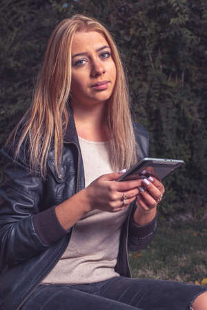 Blond haired lady doing e-learning in the park via her tablet PC. Vintage looking matte style image.の写真素材