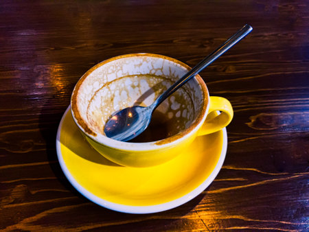 Empty coffee cup with spoon on dark wooden tabletop at coffee shopの写真素材
