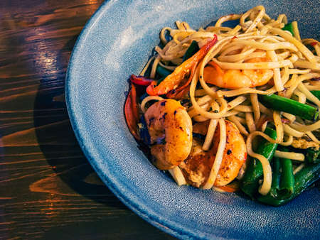 A bowl of delicious udon noodles with shrimps and vegetables, copyspace on tableの写真素材