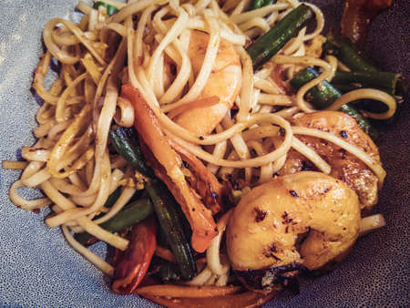 Udon noodles with fryed shrimp and vegetables close-up above top view.の写真素材