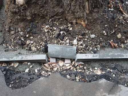 Curb stone installation. Damaged asphalt surface and bare ground around. Copyspace.
