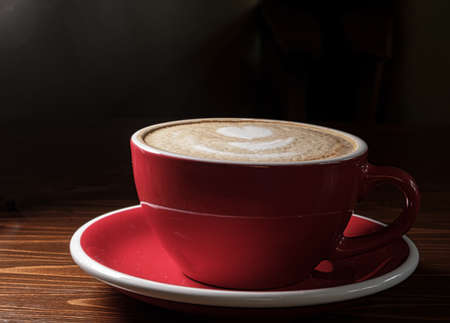 Coffee cup red color on sourcer in the dark room on deskの写真素材