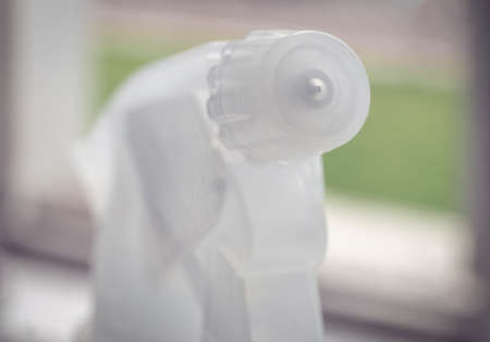 Sprayer head on windowsill macro image, green lan on background.