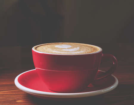 Coffee in red cup on desk, dark background with copyspaceの写真素材