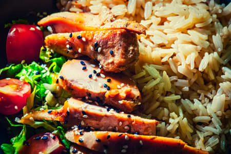 Asian food. Chicken breast with basmati rice and vegetables served in bowl on wooden table.の写真素材