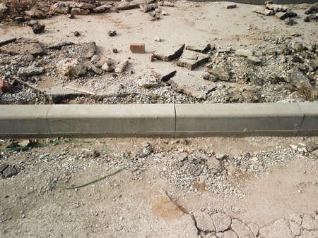 Road reconstruction. New curbstone installed and ready to be fixed with concrete, copyspace. Broken asphalt all about.の写真素材
