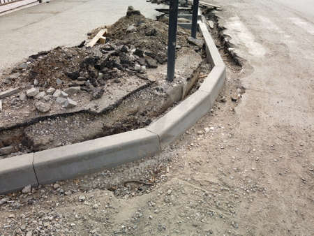 Road reconstruction. New curbstone installed and ready to be fixed with concrete, copy-space. Old asphalt surface damaged.の写真素材