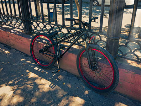 Urban transport. Black mountin bicycle parked against metal fence. Modern bicycle with lock parking in the city.の写真素材