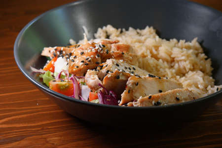 Tasty curry indian food - bowl of spicy stir rice with chicken and vegetables on wooden tableの写真素材