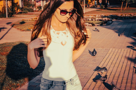 Young woman walking outside on alley with doves, blurred female, unusual shot. Copyspace.の写真素材
