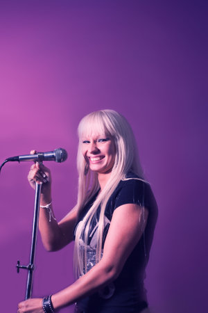 Close up photo beautiful funky blond lady on karaoke night hang out having fun playing rock star, casual black t-shirt over pink and violet background copyspace on top mock-upの写真素材