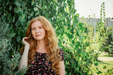 Thoughtful lady posing in front of birch tree in city park.の写真素材
