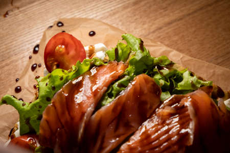 Closeup on waffle toast with tomato and salad on salmon served on a wooden rustic cutting board.の写真素材