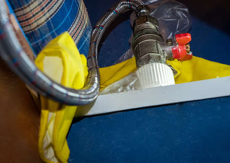 Flexible pipe connected to red water valve from below viewing.