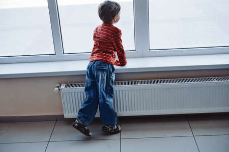 Cute boy waiting at the airport looking at window and enjoying planes arriving, rear view.の写真素材