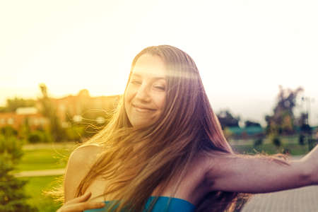 Nice blond haired lady closed eyes posing outside in the park backlit by summer sun.の写真素材