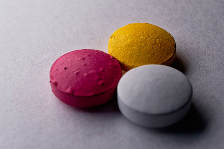Macro of white red yellow medical pill tablet on white backdrop.の写真素材