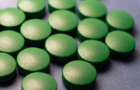 A macro shot of a green pill on a blue background. A lot of big green tablets spread over surface.の写真素材